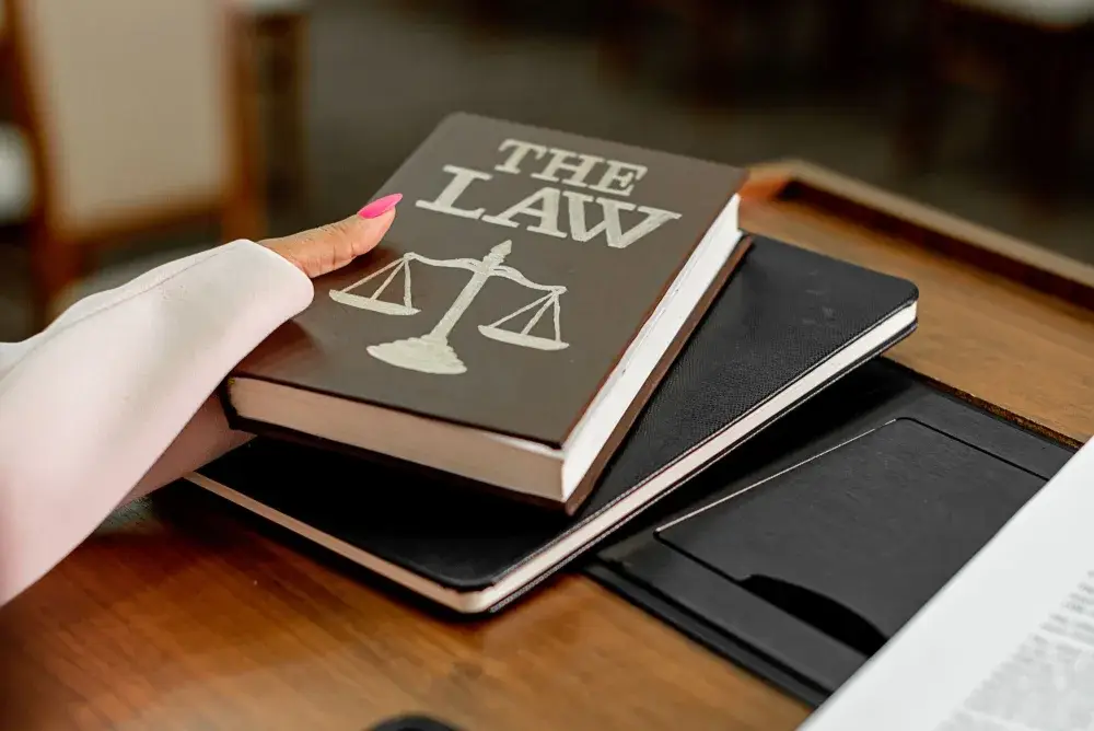 Livre de droit posé sur un bureau en bois à côté d’une balance de la justice