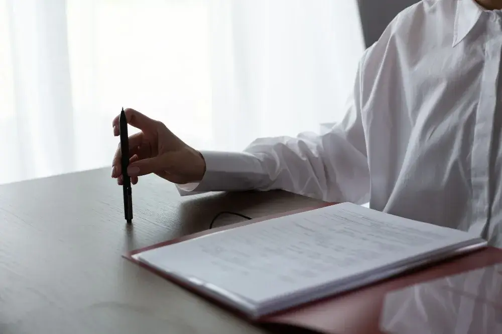 Main qui tient un stylo au-dessus de documents posés sur une table lumineuse