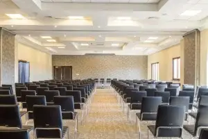 Salle de réunion vide avec des chaises noires alignées autour de tables