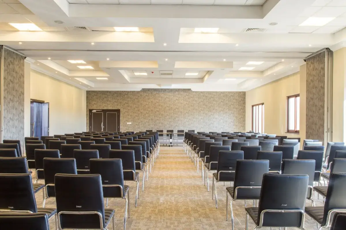 Salle de réunion vide avec des chaises noires alignées autour de tables