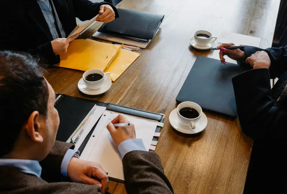 Collègues assis autour d’une table avec des documents et du café, vus de dessus